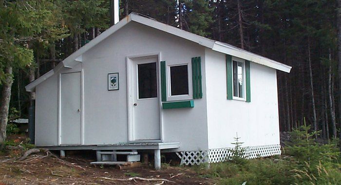 Petit camp blanc aux volets verts dans les bois